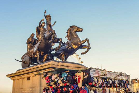 Bronze statue of Boudica and her daughters in a chariot beside Westminster Bridge in London, with the London Eye visible behind.