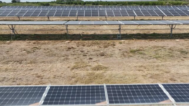 Flyover consecutive rows of solar panels aimed toward sun clean energy