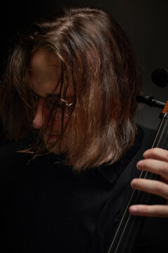 Vertical shot of young Caucasian musician playing double bass during musical rehearsal. Creative imagery suitable for classical concert advertising and arts education campaigns