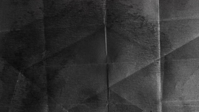 Abstract dark black paper texture with geometric folds.