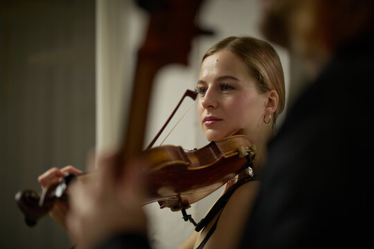 Caucasian young adult woman playing violin during music rehearsal. Concept representing dedication to classical arts, suitable for concert advertising, cultural branding, or music education