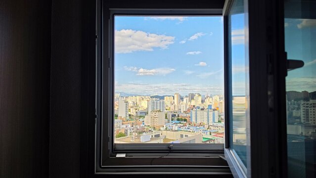 View of a sunny blue sky and city skyline through an open window