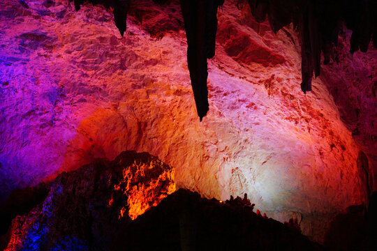 Illuminated Limestone Cave Interior with Stalactites and Dramatic Rock Formations