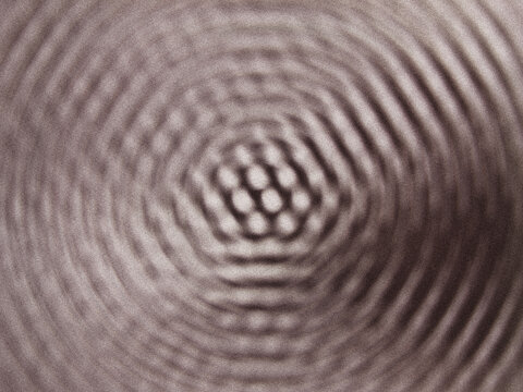 Interference pattern of concentric circular waves creating a central hexagonal lattice