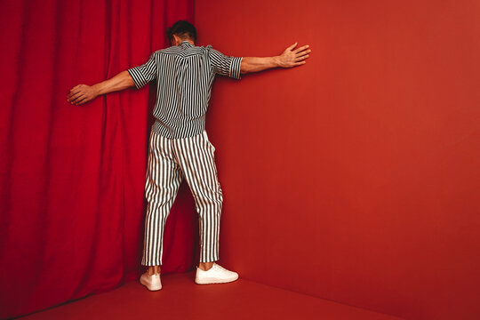 Person in striped clothing standing in red corner showing despair and burnout