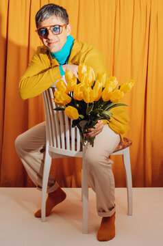 Man with yellow tulips sitting on chair in retro indoor setting