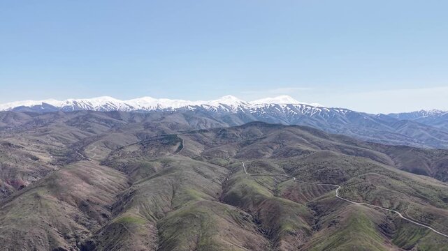 Smooth 4K aerial approach toward Palu Castle during spring, revealing green valleys, open agricultural fields and a clear blue sky in bright daylight.