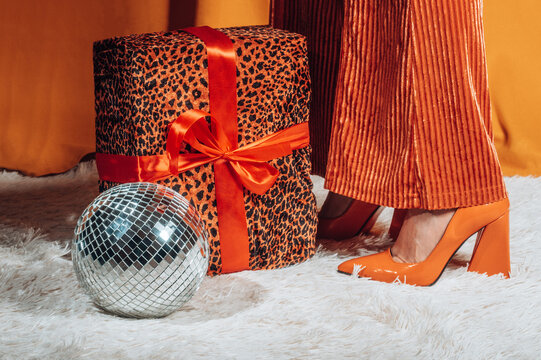 Woman stands by a leopard print gift and disco ball at a party