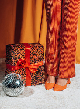 Woman stands indoors with a retro gift box and a disco ball