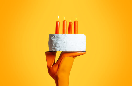 Woman balances a birthday cake on her orange boot