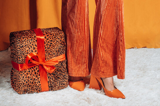 Woman stands next to a leopard print gift in retro orange clothing
