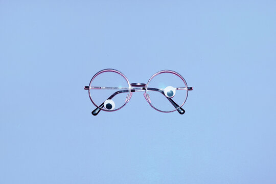 Round glasses with googly eyes sit on a blue background