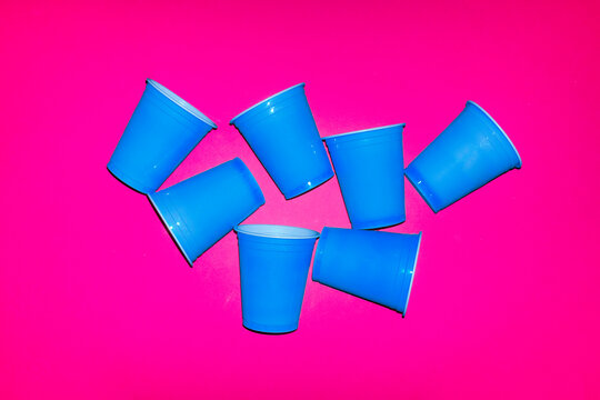 Several blue plastic cups cover a bright pink background