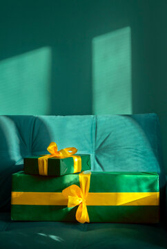 Two green gifts with yellow ribbons lie on a couch at home