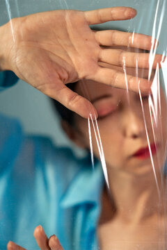 A woman presses her hand against a suffocating plastic film