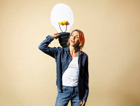 Mature woman in jeans holding a paper light bulb for a creative idea