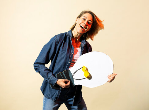 Smiling woman holds a large paper light bulb showing creativity