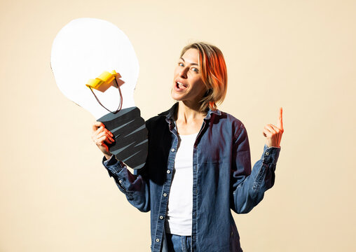 Woman holds a paper lightbulb and points finger up for a new idea