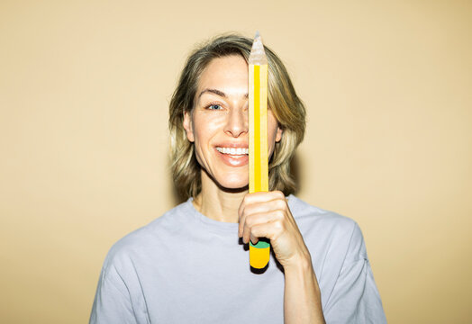 Woman holds an oversized pencil indoors for creative brainstorming