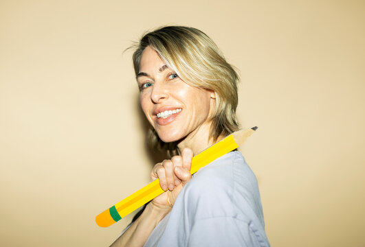 Smiling woman holds a giant paper pencil during brainstorming