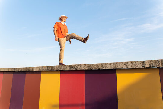 Happy man balances on a colorful wall at F�rum Park in Barcelona