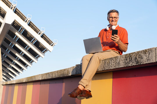 Man working on laptop and smartphone at F�rum Park Barcelona