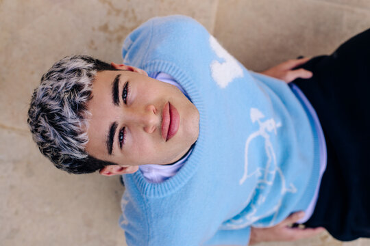 Confident young man sitting outdoors on steps looking at camera