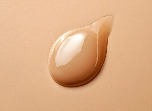 Macro shot of liquid silk foundation droplet gliding on smooth skin texture