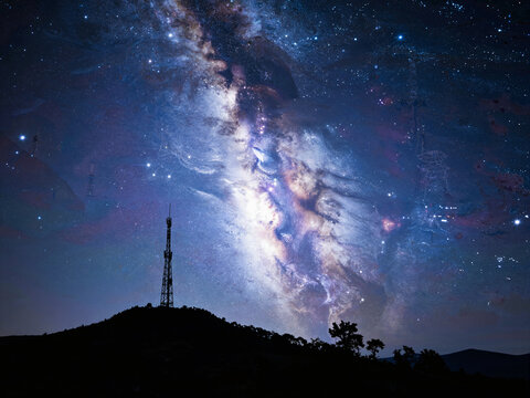 Silhouette of a radio tower against the Milky Way galaxy in the night