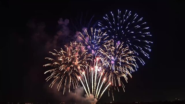 Spectacular fireworks explode in night sky creating beautiful bursts of light and color for celebration and holidays.