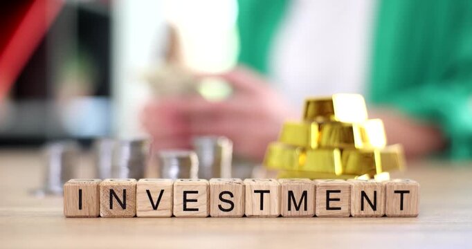 Glistening gold and silver bars are arranged on a wooden table as the concept of investment unfolds. The hands of a person are engaged, showcasing the excitement of financial growth.