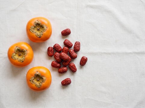 Minimalist Chuseok harvest composition with fresh persimmons and jujubes on white background