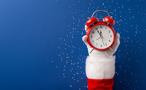 Merry Christmas and Happy New Year message from Santa Claus holding a red alarm clock for festive countdown
