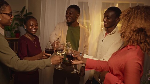 African American young adults smiling and clinking wine glasses during holiday celebration party. Footage serves beverage advertising, social gathering campaigns, and friendship storytelling