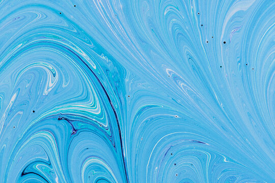 Fluid blue paint pattern featuring swirling light aqua waves, white accents, and subtle dark streaks.