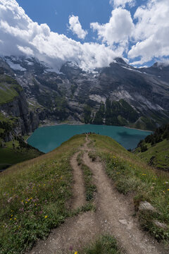 Narrow footpath descending toward a vivid turquoise mountain lake