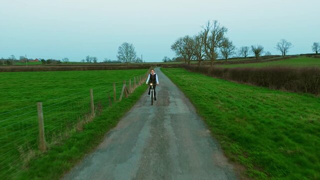 Cyclist woman riding bicycle along rural road at dusk with bicycle headlight shining, healthy lifestyle cardio workout. Evening outdoor cycling training burning fat calories, active leisure fitness