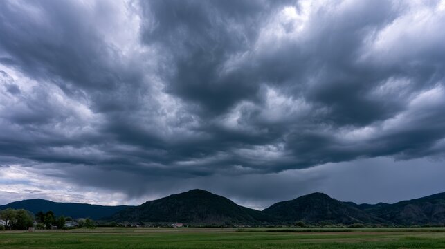 Dramatic Sky Over Mountains with Dark Storm Clouds Rolling Above a Green Valley Landscape Preparing for a Change in Weather Conditions