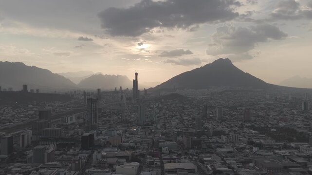 Aerial panorramic view in Monterrey, Mexico, drone flying backwards with views of the skyscrapers and mountains during sunset, raw clip shot on D-Log M