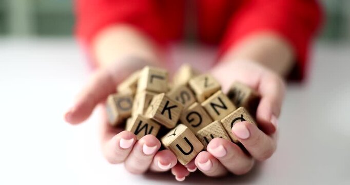 Hands filled with colorful wooden blocks, each marked with letters, invite playful exploration. The cozy indoor environment enhances the charm of this engaging activity.