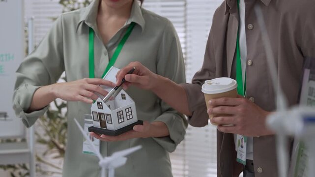 Asian employee and coworker discussing ESG report during professional office meeting over coffee cups, creating friendly workplace conversation, collaboration, sustainability planning, and modern