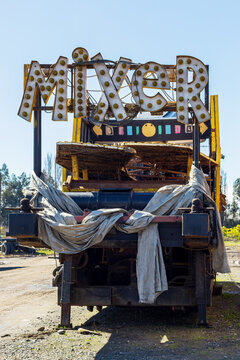 An abandoned amusement ride marked &ldquo;MIXER,&rdquo; showing rusted metal, worn tarps, and faded bulbs against a bright Angol sky