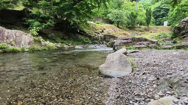 Calm clear river flowing past a stone bank in Hinohara village Tokyo