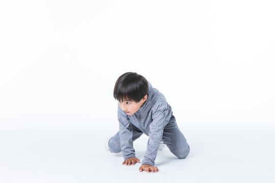 Young boy in grey onesie on all fours