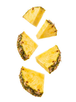 Fresh ripe pineapple slices and wedges falling and floating in the air, isolated on transparent background.