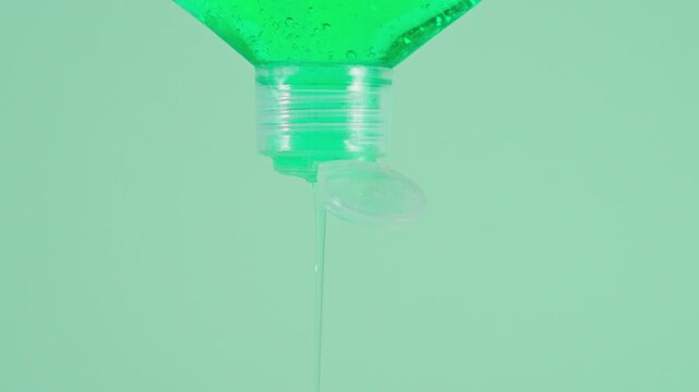Close up of Dish soap flowing from inverted bottle against blue background