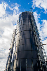 Low angle view of tall agricultural storage silos reaching into blue sky. © Octavian