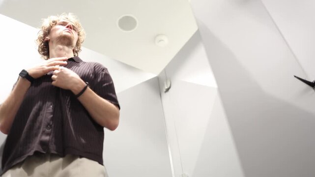 Student checks how a T shirt fits from the back while trying on clothes carefully studying the silhouette comfort and overall appearance before deciding whether to buy it