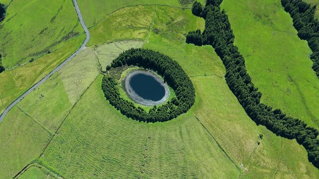 Aerial view over lush Sao Miguel volcanic landscape and round Pau Pique lake in caldera in lush Azores landscape