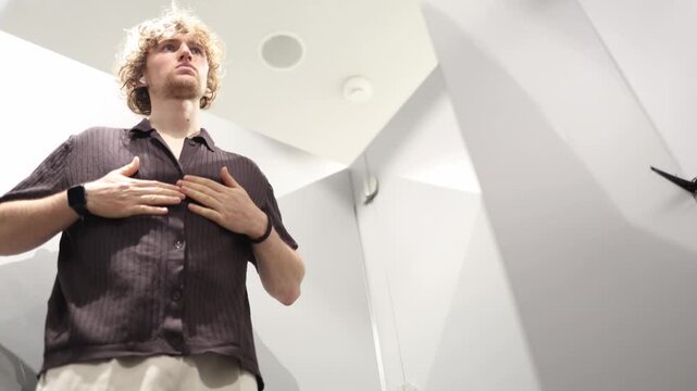 Man adjusts the neckline of a T shirt while trying on clothes carefully checking collar fit comfort and appearance to decide whether the item feels right before buying it